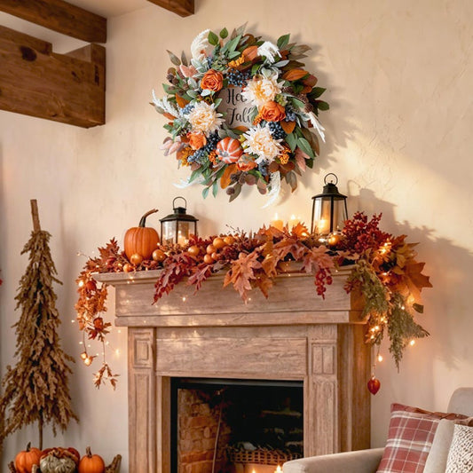 An autumn-themed floral wreath with the words 'The Fall is Love' hangs on a beige wall above a rustic wooden fireplace mantel decorated with fall leaves, pumpkins, lanterns, and fairy lights.